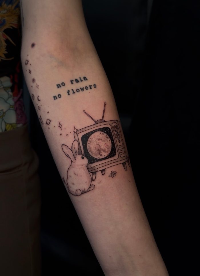 Tatuaggio con televisore e scritta sull'avambraccio